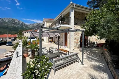 a house with a bench and an umbrella on a patio at Sutorman 1 Villa D&B in Zupci
