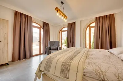 a bedroom with a bed and a chair and windows at Sutorman 1 Villa D&B in Zupci