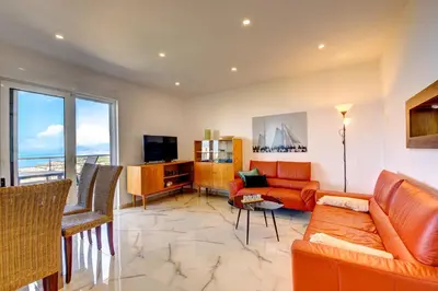 a living room with orange furniture and a large window at Jana in Utjeha