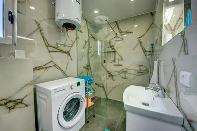 a bathroom with a washing machine and a sink at Jana in Utjeha