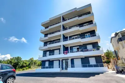 a building with balconies and a car parked in front at Jana in Utjeha