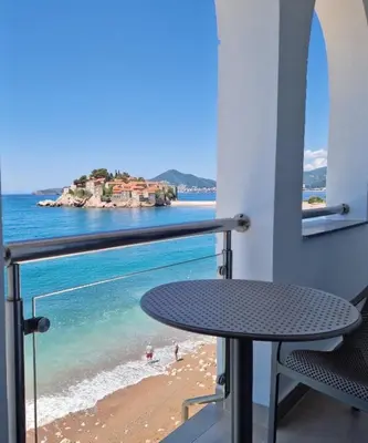 a balcony with a table and a view of the beach at Beach apartment Sveti Stefan in Sveti Stefan
