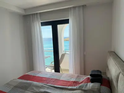 a bedroom with a bed and a view of the ocean at Beach apartment Sveti Stefan in Sveti Stefan