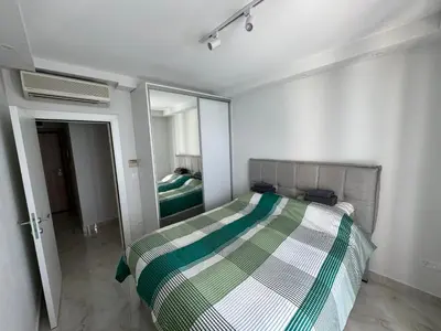 a bedroom with a green and white bed and a mirror at Beach apartment Sveti Stefan in Sveti Stefan