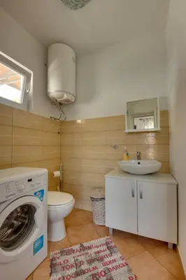 a bathroom with a washing machine and a toilet at Sun & Sea in Utjeha