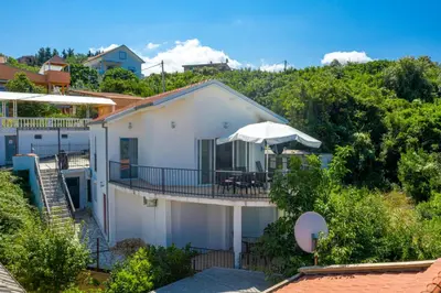 a white house with a deck with an umbrella at Sun & Sea in Utjeha
