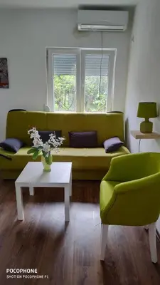 a living room with a green couch and a table at Stan na dan Podgorica in Podgorica