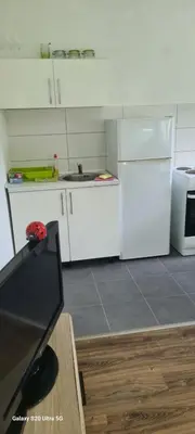 a white kitchen with a sink and a refrigerator at Stan na dan Podgorica in Podgorica