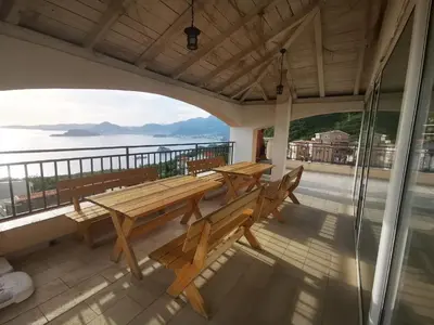a wooden table on a balcony with a view of the water at Villa Anlave in Sveti Stefan