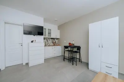 a kitchen with white cabinets and a table in it at Apartments Milivojevic in Bar