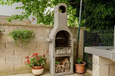 a stone pizza oven with some plants and flowers at Apartments Milivojevic in Bar