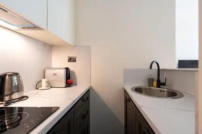 a white kitchen with a sink and a microwave at Invictus Hotel in Budva