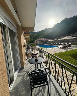 a balcony with a table and chairs and a pool at Etno Selo Grabovicka Jutra in Cetinje