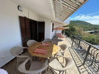 a wooden table and chairs on a balcony at Villa Galatea in Utjeha