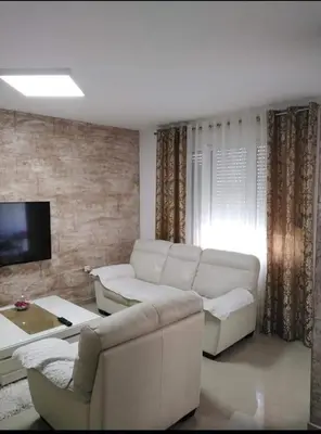 a living room with a white couch and a tv at D&D Apartman in Bar