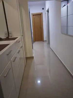 a kitchen with white cabinets and a hallway with a door at D&D Apartman in Bar