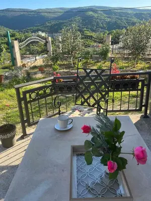 a table with a cup and a vase with flowers on it at Sunny Hill - Parking - Fenced Garden - Luxury Loft in Kotor