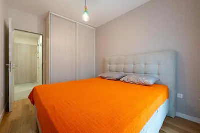 a bedroom with a bed with an orange blanket at Geppetto Apartment in Podgorica