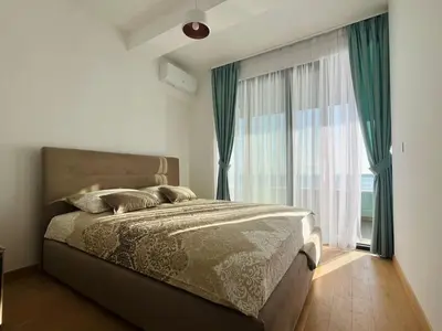 a bedroom with a bed and a large window at Rafailovici Beachfront Apartment in Budva