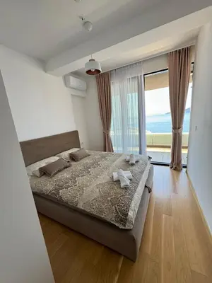 a bedroom with a bed and a large window at Rafailovici Beachfront Apartment in Budva