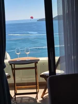 two wine glasses sitting on a table in front of a window at Rafailovici Beachfront Apartment in Budva