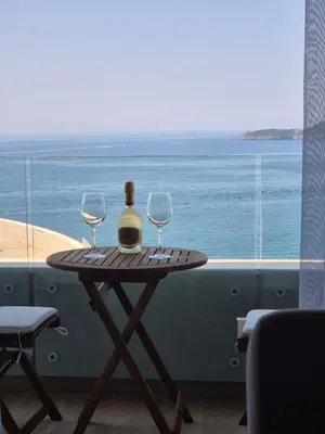 a table with two glasses and a bottle of wine at Rafailovici Beachfront Apartment in Budva