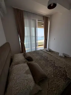 a bedroom with a large bed with a large window at Rafailovici Beachfront Apartment in Budva