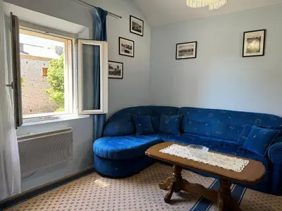 a living room with a blue couch and a table at Santa Maria - Old Town Apartment in Budva