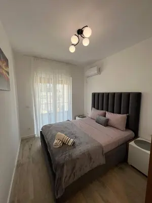 a bedroom with a large bed with a black headboard at Frekuenca Apartments in Ulcinj