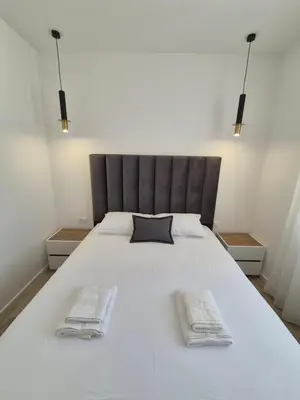 a bedroom with a large white bed with two towels at Frekuenca Apartments in Ulcinj