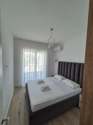 a bedroom with a large bed with white sheets and a window at Frekuenca Apartments in Ulcinj