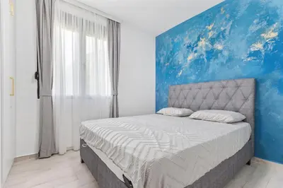 a bedroom with a bed with a blue painting on the wall at ALISA Sea View Apartment in Kotor