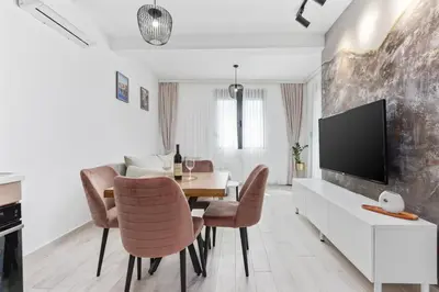 a dining room with a table and chairs and a tv at ALISA Sea View Apartment in Kotor