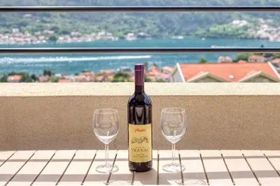 a bottle of wine and two wine glasses on a table at ALISA Sea View Apartment in Kotor