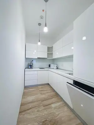 a kitchen with white cabinets and a wooden floor at Apartment in Tre Canne in Budva