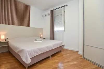 a white bedroom with a bed and a window at Dolami residence in Becici