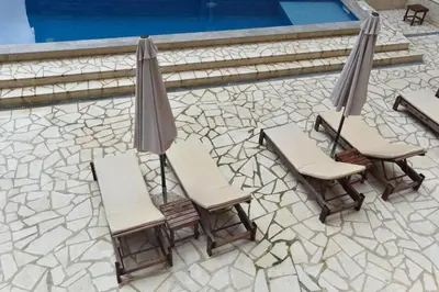 two chairs and two umbrellas next to a pool at Dolami residence in Becici