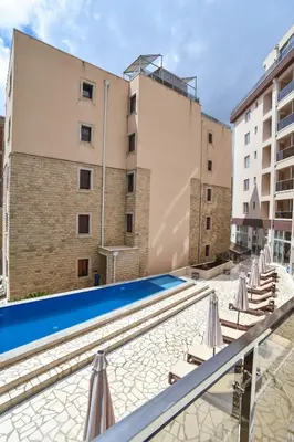 a swimming pool with lounge chairs and a building at Dolami residence in Becici