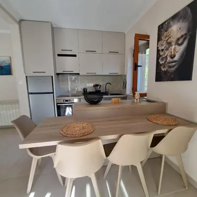 a kitchen with a wooden table and white chairs at Bubi in Kotor