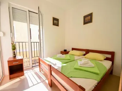 a bedroom with a bed with green sheets and a window at Apartment Anlave in Sveti Stefan