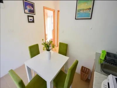 a white table and green chairs in a room at Apartment Anlave in Sveti Stefan