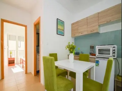 a kitchen with a white table and green chairs at Apartment Anlave in Sveti Stefan
