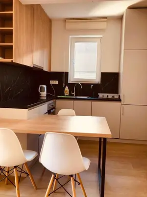 a kitchen with a wooden table and white chairs at DH Horizon Residences in Budva