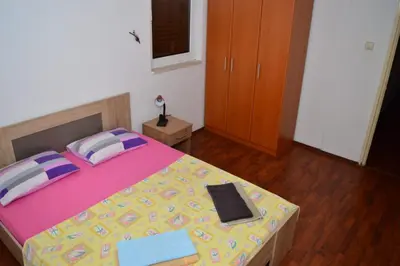 a bedroom with a bed with a pink and yellow comforter at Apartments Moreno in Budva