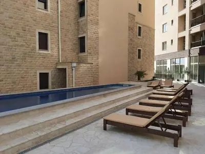 a swimming pool in a building with lounges and chairs at Apartment Becici in Becici