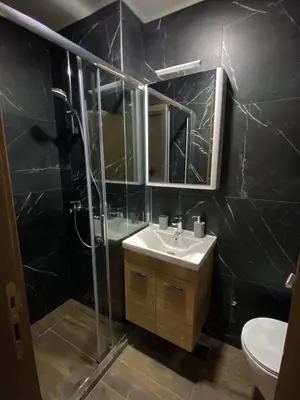 a black tiled bathroom with a sink and a shower at Masha Apartment in Budva
