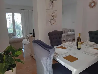 a dining room and living room with a white table and chairs at Apartment deluxe Ina FREE PARKING in Budva