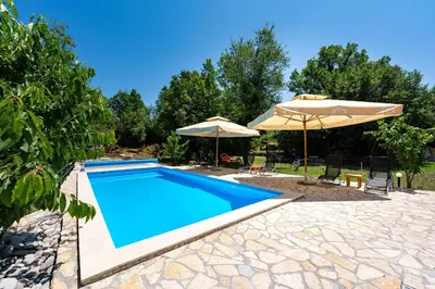a swimming pool with umbrellas and chairs and a pool at NAJ village in Cetinje