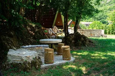 a table and stools in a yard with a tree at NAJ village in Cetinje