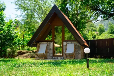 a small house with two chairs in the grass at NAJ village in Cetinje